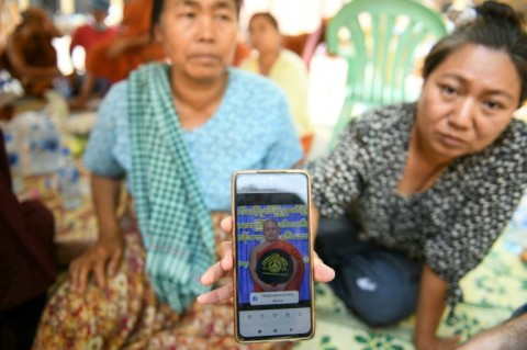 A woman shows a picture of a missing monk during search and rescue operations at a damaged temple in Mandalay