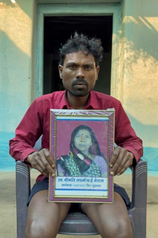 Farmer Mohan Singh Gond holds the portrait of his late mother Lakshmibai Gond, who was trampled by elephants while watching her fields