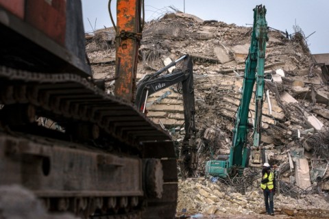 A rescue worker gestures past heavy machinery used to find people trapped in the rubble in Bangkok