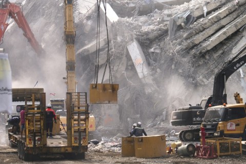 Heavy construction equipment is used to clear the debris at the site of the collapsed building in Bangkok