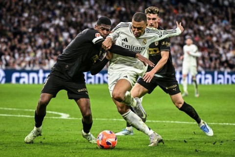 Kylian Mbappe struggles to escape the grasp of Valencia's Cristhian Mosquera (left)