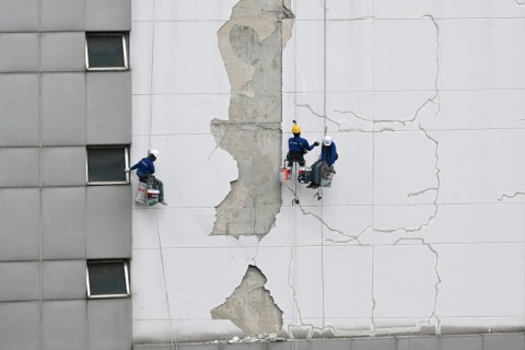 Workers repair damage on the exterior of a high-rise building in Bangkok following the March 28 earthquake