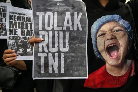 Students displaying placards reading "return the soldiers to the barracks" during a protest against a revision to the armed forces law in Surabaya