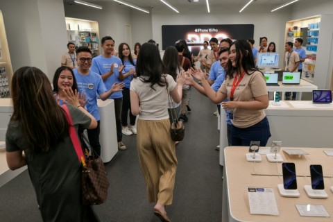 Employees welcome customers entering their store which sells the Apple iPhone 16 in Jakarta on April 11, 2025