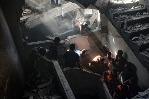 Residents and rescuers inside a building hit by an Israeli strike in Gaza City's Shujaiya district on April 10