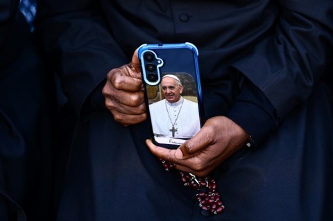 A pilgrim holds a smartphone with a picture of Pope Francis