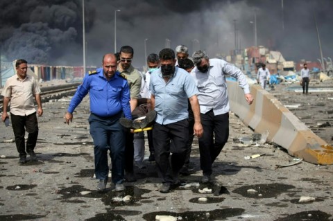 People transport an injured man following the explosion at the Shahid Rajaee port