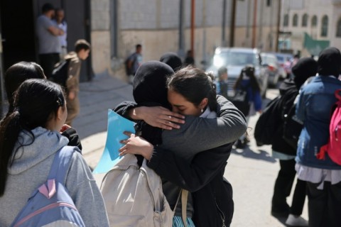 Palestinian schoolgirls embrace as they leave a UNWRA school