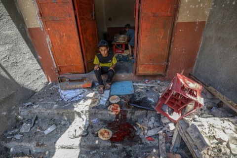 Palestinian boys salvage bread from a makeshift bakery hit in Israeli strikes in the central Gaza Strip