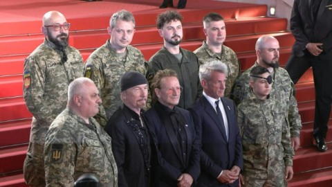 Bono, The Edge and US actor Sean Penn pose with Ukrainian soldiers on the Cannes red carpet