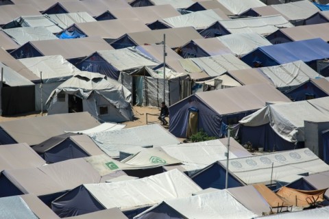 A Palestinian man sits amid tents at a camp for displaced people in Gaza City