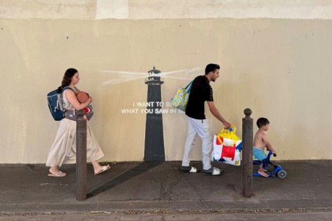 Pedestrians walk past a newly released artwork by street artist Banksy on the facade of a building in Marseille in southern France
