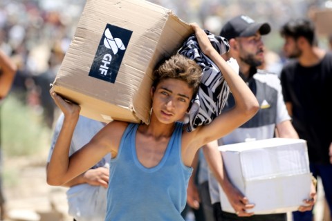A boy carries a box of relief supplies from the Gaza Humanitarian Foundation in the central Gaza Strip