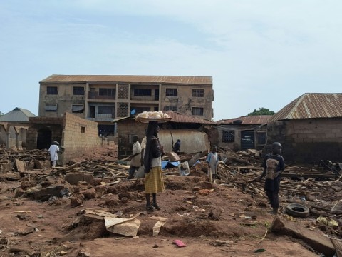A woman stands next to debris from damaged buildings in Mokwa, Nigeria, where many bodies are feared to be buried in the rubble following deadly flooding