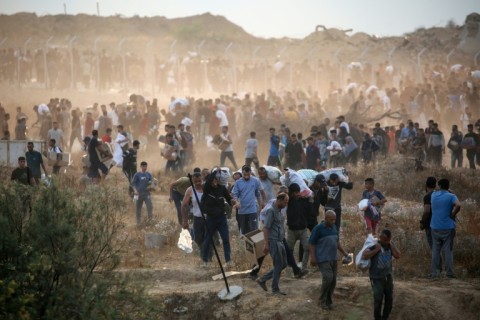 Palestinians carry supplies from a Gaza Humanitarian Foundation aid point in the central Gaza Strip