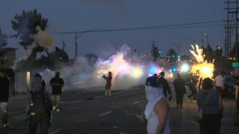 Demonstrators smash the windshield of a vehicle next to a burning self-drive vehicle as protesters clash with law enforcement in Los Angeles, California, on June 8, 2025