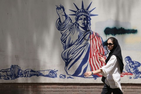 A woman walks past an anti-US mural near the former US embassy in Tehran