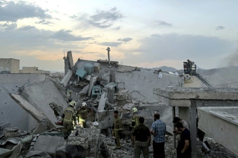 First responders clamber over the rubble of a Tehran building hit by an Israeli strike.