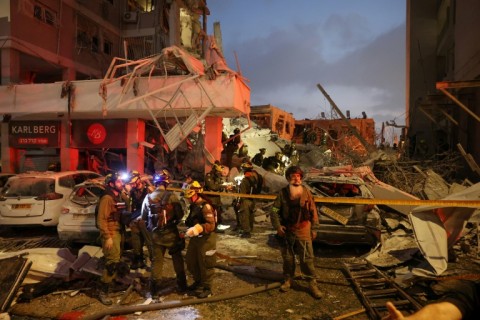 Responders work beside a damaged building following a strike by an Iranian missile in the Israeli city of Bat Yam
