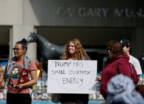 A protester holds a sign during a demonstration in front of Calgary City Hall on June 15, 2025 as world leaders converge in Canada for the G7 Summit