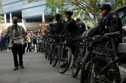 A protester beats on a drum in front of a line of police during a demonstration in front of Calgary City Hall on June 15, 2025, as world leaders converge in Canada for the G7 Summit