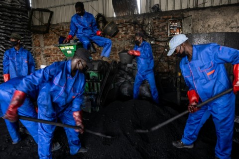 Workers put a mixture of burnt agricultural waste and binders into a coal press