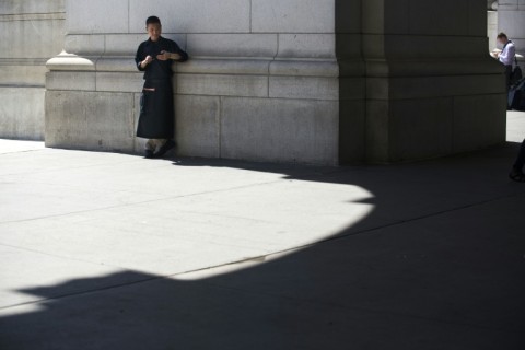 A chef takes a break to check his phone in a sliver of shade outside Union Station on August 12, 2016 in Washington,DC