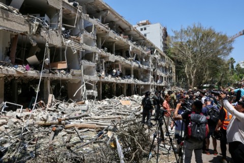 Israeli security forces and media gather at the site of an Iranian strike that hit a residential neighbourhood in the Ramat Aviv area in Tel Aviv