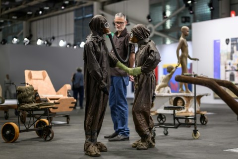 An Art Basel visitor has a close look at part of 'The Voyage -- A March To Utopia', by Atelier Van Lieshout