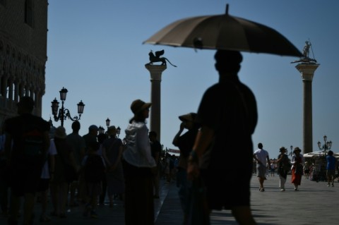 A man in Venice uses an umbrella to protect himself from the heat