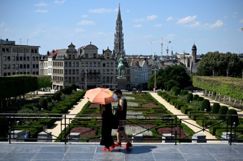 A woman walks with an umbrella past the Jardin du Mont des Arts as temperatures reach 37 degrees Celsius in Brussels