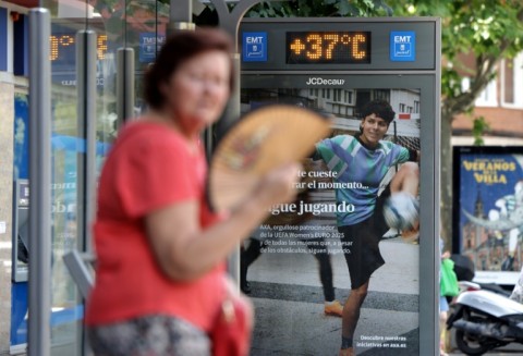 A woman fans herself at a bus stop in Madrid