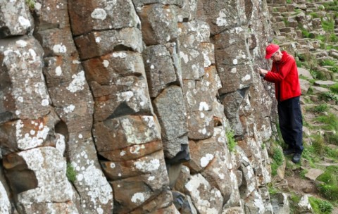 Cliff Henry looks for coins left by tourists in the cracks of the stones