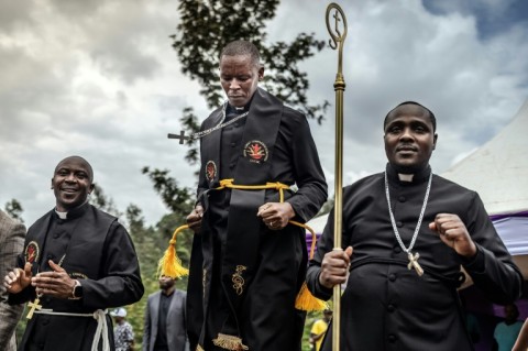 A priest jumps as mourners pray and dance during the funeral of Boniface Kariuki