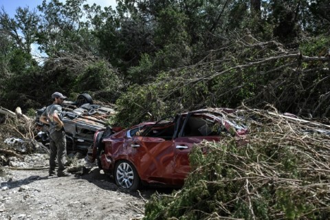 A man searches for missing people by a crushed car near the Guadalupe River in Hunt, Texas
