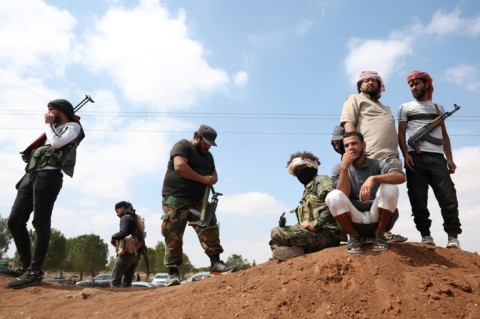 Tribal fighters stand next to a government checkpoint east of Sweida city, in southern Syria