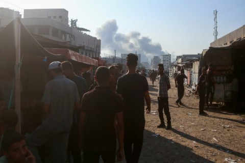 Displaced Gazans look on as smoke billows over the southern city of Khan Yunis following Israeli strikes.