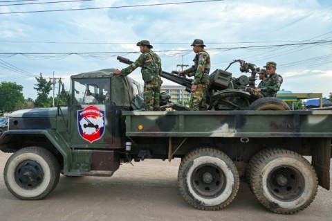 Cambodian soldiers stand on a military truck with an anti-aircraft gun in Oddar Meanchey province