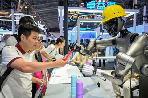 People watch a robot performing tasks at an exhibition during the World AI Conference in Shanghai