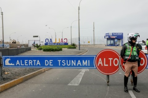 A Peruvian traffic police officer sets up a roadblock during a tsunami warning in La Punta, Callao province