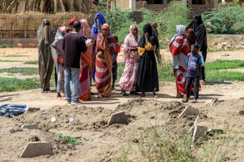 Bereaved relatives gather by the makeshift graves, waiting for the chance to give their loved ones a proper burial