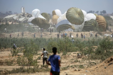 Palestinians rush to the site where parachuted aid packages in the Nuseirat area in the central Gaza Strip