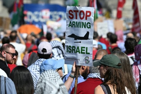A protestor with a sign that reads 'Stop arming Israel' at a Berlin protest in June