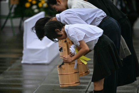 Schoolchildren make a ceremonial water offering during a memorial event marking the 80th anniversary of the US atomic bombing of Nagasaki