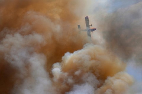 A firefighter airplane flies over a wildfire near the village of Abejera, Spain on August 13, 2025