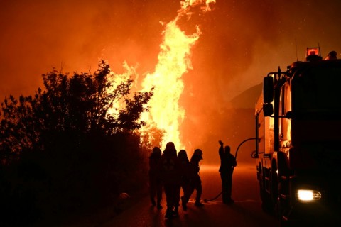 Firefighters work to extinguish a wildfire near the city of Patras, western Greece, on August 13, 2025