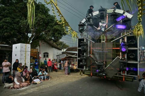 Crew members sit atop a truck mounted with a tower of subwoofers used at Independence Day celebrations in Malang, East Java