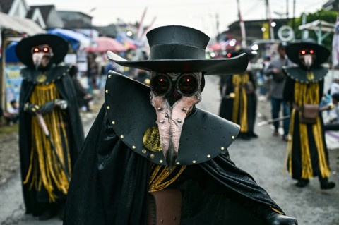 Costumed dancers perform as they follow a truck mounted with a tower of subwoofers and spotlights during a "sound horeg"