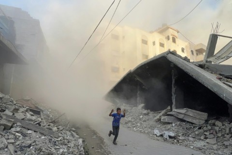A Palestinian boy rushes away from the site of Israeli air strikes on a six-storey building in the Saftawi neighborhood west of Jabalia
