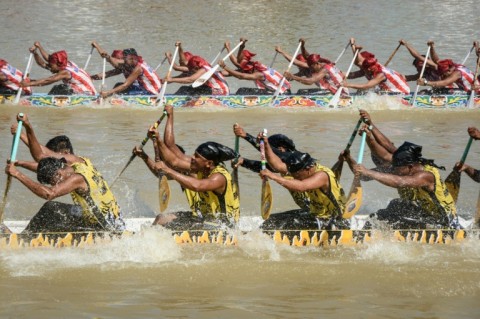 Participants paddle hard on their boat during the race held on the Kuantan River
